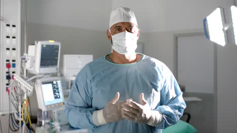 Portrait-of-african-american-male-surgeon-wearing-surgical-gown-in-operating-theatre,-slow-motion