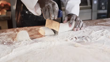 Diverse-bakers-working-in-bakery-kitchen,-cutting-dough-on-counter-in-slow-motion