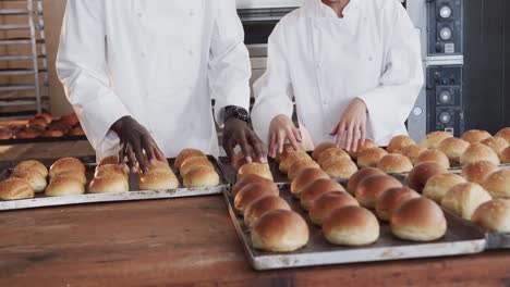 Happy-diverse-bakers-working-in-bakery-kitchen,-counting-fresh-rolls-in-slow-motion