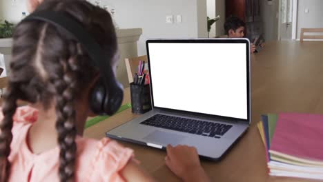 Composition-of-biracial-schoolgirl-on-laptop-online-learning-with-blank-screen
