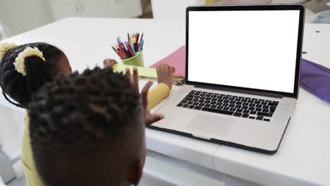 Composition-of-african-american-schoolgirl-and-schoolboy-on-laptop-online-learning-with-blank-screen