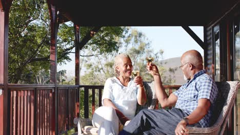 Glückliches-älteres-Afroamerikanisches-Paar,-Das-Wein-Auf-Der-Sonnigen-Terrasse-Trinkt,-Zeitlupe