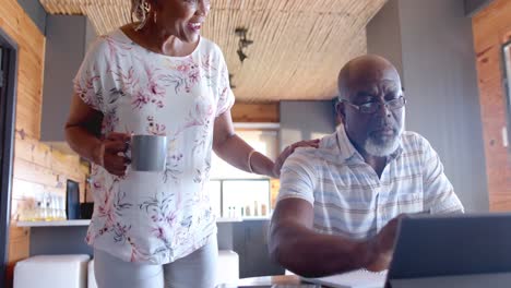 Senior-african-american-couple-doing-paperwork-using-tablet-at-home,-slow-motion