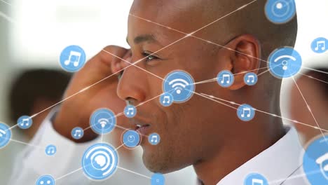 Animation-of-network-of-digital-icons-against-african-american-businessman-talking-on-smartphone