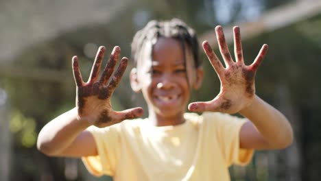 Portrait-of-happy-african-american-boy-showing-hands-covered-with-soil,-slow-motion