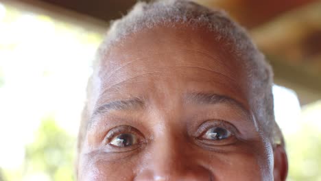 Portrait-of-happy-eyes-of-senior-african-american-woman-on-sunny-terrace,-slow-motion