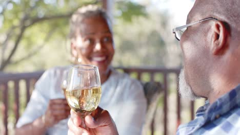 Glückliches-älteres-Afroamerikanisches-Paar,-Das-Wein-Auf-Der-Sonnigen-Terrasse-Trinkt,-Zeitlupe