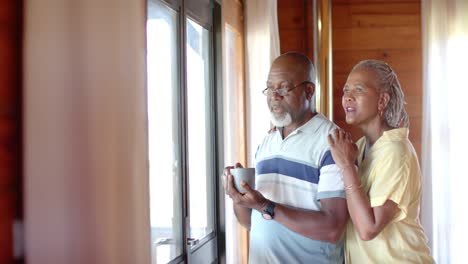 Senior-african-american-couple-talking-and-looking-out-window-at-home,-slow-motion