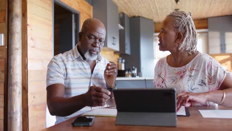 Senior-african-american-couple-doing-paperwork-using-tablet-at-home,-slow-motion