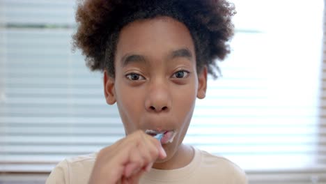 Portrait-of-african-american-boy-brushing-teeth-in-bathroom,-slow-motion