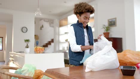 Happy-african-american-boy-sorting-waste-in-kitchen,-slow-motion