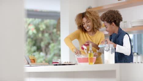 Happy-african-american-mother-and-son-baking-in-kitchen,-slow-motion