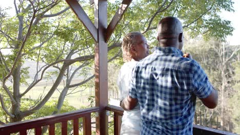 Glückliches-älteres-Afroamerikanisches-Paar,-Das-Sich-Auf-Der-Sonnigen-Terrasse-Umarmt-Und-Wein-Trinkt,-Zeitlupe