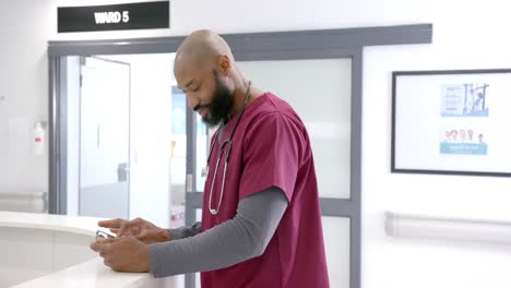 Portrait-of-happy-african-american-male-doctor-using-tablet-in-hospital-reception,-slow-motion
