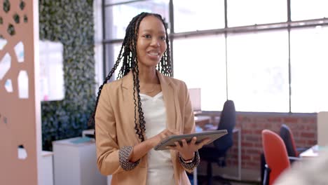 Mujer-De-Negocios-Informal-Afroamericana-Usando-Tableta-Y-Hablando-En-La-Oficina