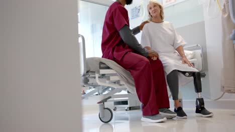 Afroamerikanischer-Arzt-Im-Gespräch-Mit-Einer-Kaukasischen-Patientin-Mit-Beinprothese-Im-Krankenhaus