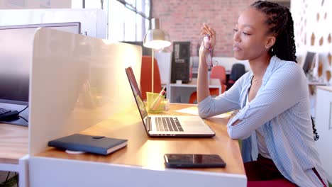 African-american-casual-businesswoman-making-video-call-using-laptop-in-office,-slow-motion