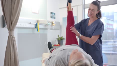 Caucasian-female-physiotherapist-stretching-prosthetic-leg-of-female-patient-at-hospital