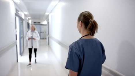 Happy-caucasian-female-doctors-greeting-each-other-in-hospital-corridor,-slow-motion