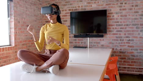 African-american-businesswoman-using-vr-headset-sitting-on-table-in-office,-slow-motion,-copy-space