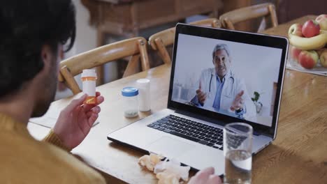 Caucasian-man-holding-medication-making-video-call-using-laptop-with-male-doctor,-slow-motion