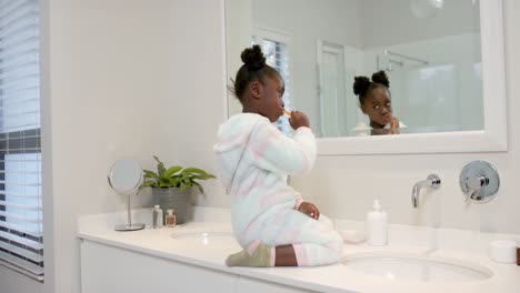 African-american-girl-brushing-teeth-in-bathroom,-slow-motion