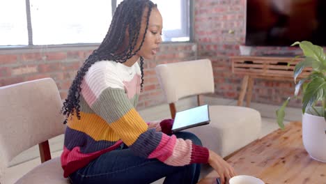 Afroamerikanische-Gelegenheitsgeschäftsfrau,-Die-Im-Büro-Ein-Tablet-Nutzt-Und-Auf-Dem-Smartphone-Spricht
