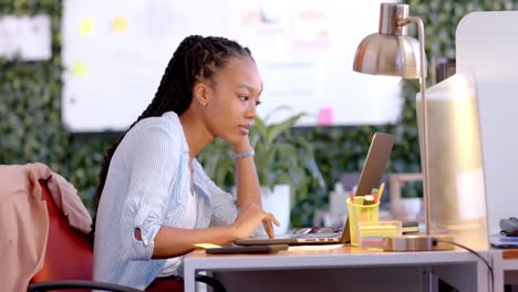 Reflexiva-Mujer-De-Negocios-Afroamericana-Casual-Usando-Laptop-En-La-Oficina,-Cámara-Lenta