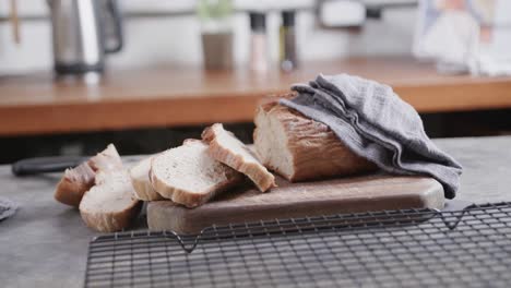 Close-up-of-sliced-bread-on-cutting-board-in-kitchen,-slow-motion