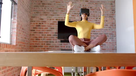 Afroamerikanische-Geschäftsfrau-Mit-VR-Headset-Sitzt-Auf-Einem-Tisch-Im-Büro,-Kopierraum,-Zeitlupe