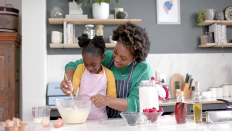 Happy-african-american-mother-and-daughter-preparing-dough-in-bowl-in-kitchen,-slow-motion