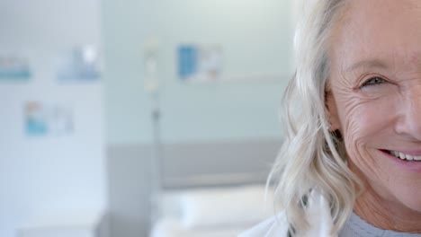 Half-portrait-of-happy-senior-caucasian-female-doctor-in-hospital-room-with-copy-space,-slow-motion