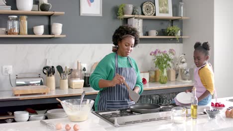 Glückliche-Afroamerikanische-Mutter-Und-Tochter,-Die-Pfannkuchen-In-Der-Küche-Braten,-Zeitlupe