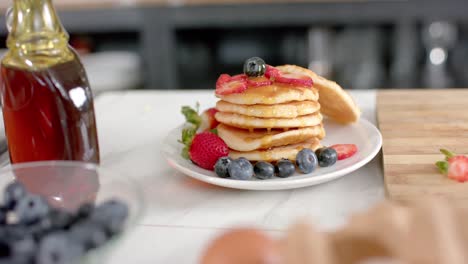 Close-up-of-pancakes-with-fruits-and-honey-in-kitchen,-slow-motion