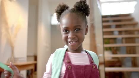Portrait-of-happy-african-american-girl-with-backpack-at-home,-slow-motion