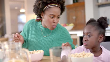 Feliz-Madre-E-Hija-Afroamericana-Comiendo-Cereal-Con-Leche-En-La-Cocina,-Cámara-Lenta