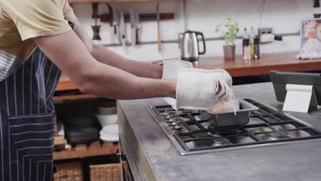 Caucasian-man-pulling-bread-out-from-oven-in-kitchen,-slow-motion