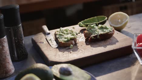 Close-up-of-avocado-toast,-vegetables-and-spices-in-kitchen,-slow-motion