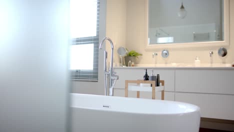 Close-up-of-sunny-white-bathroom-with-freestanding-bathtub,-slow-motion