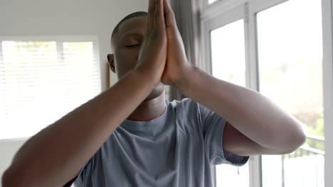 African-american-man-doing-yoga-and-meditating-at-home,-slow-motion