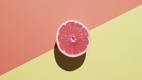 Video-Von-Geschnittenen-Roten-Grapefruits-Mit-Kopierraum-Auf-Orangefarbenem-Und-Gelbem-Hintergrund