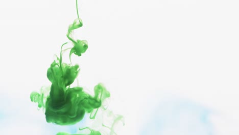 Slow-motion-video-of-green-watercolor-ink-mixing-in-water-against-grey-background