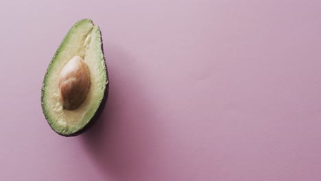 Video-of-sliced-avocado-with-copy-space-over-pink-background