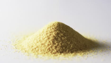 Video-of-close-up-of-heap-of-yellow-sand-grains-and-copy-space-on-white-background