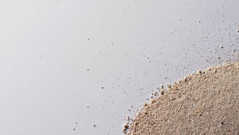 Video-of-close-up-of-heap-of-sand-grains-and-copy-space-on-white-background