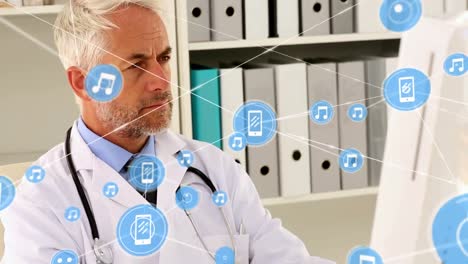 Animation-of-network-of-digital-icons-over-caucasian-senior-male-doctor-using-computer-at-hospital