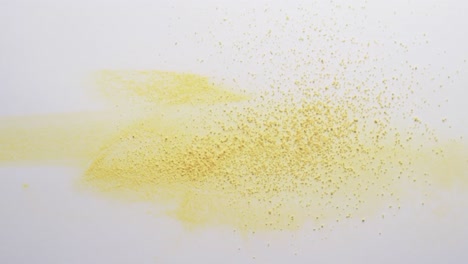 Video-of-close-up-of-yellow-sand-grains-and-copy-space-on-white-background