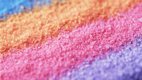Video-of-close-up-of-rainbow-coloured-sand-grains-and-copy-space-background