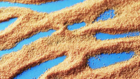 Video-of-close-up-of-pattern-of-yellow-sand-grains-and-copy-space-on-blue-background