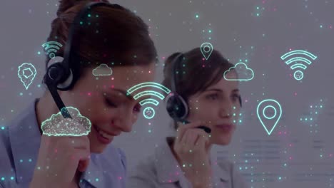 Animation-of-multiple-neon-digital-icons-over-two-diverse-women-talking-on-phone-headset-at-office